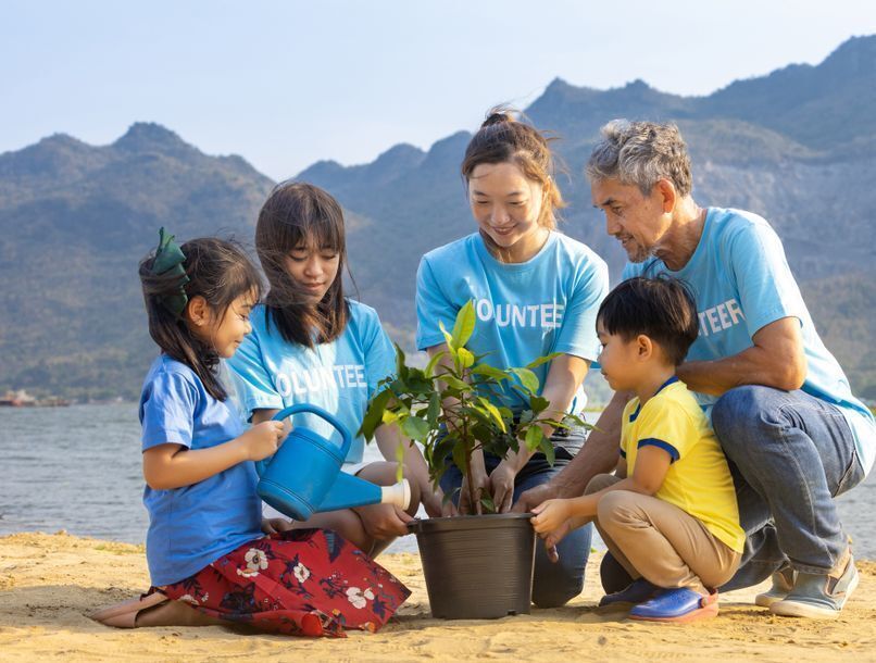 Group of adults and kids planting a flower.