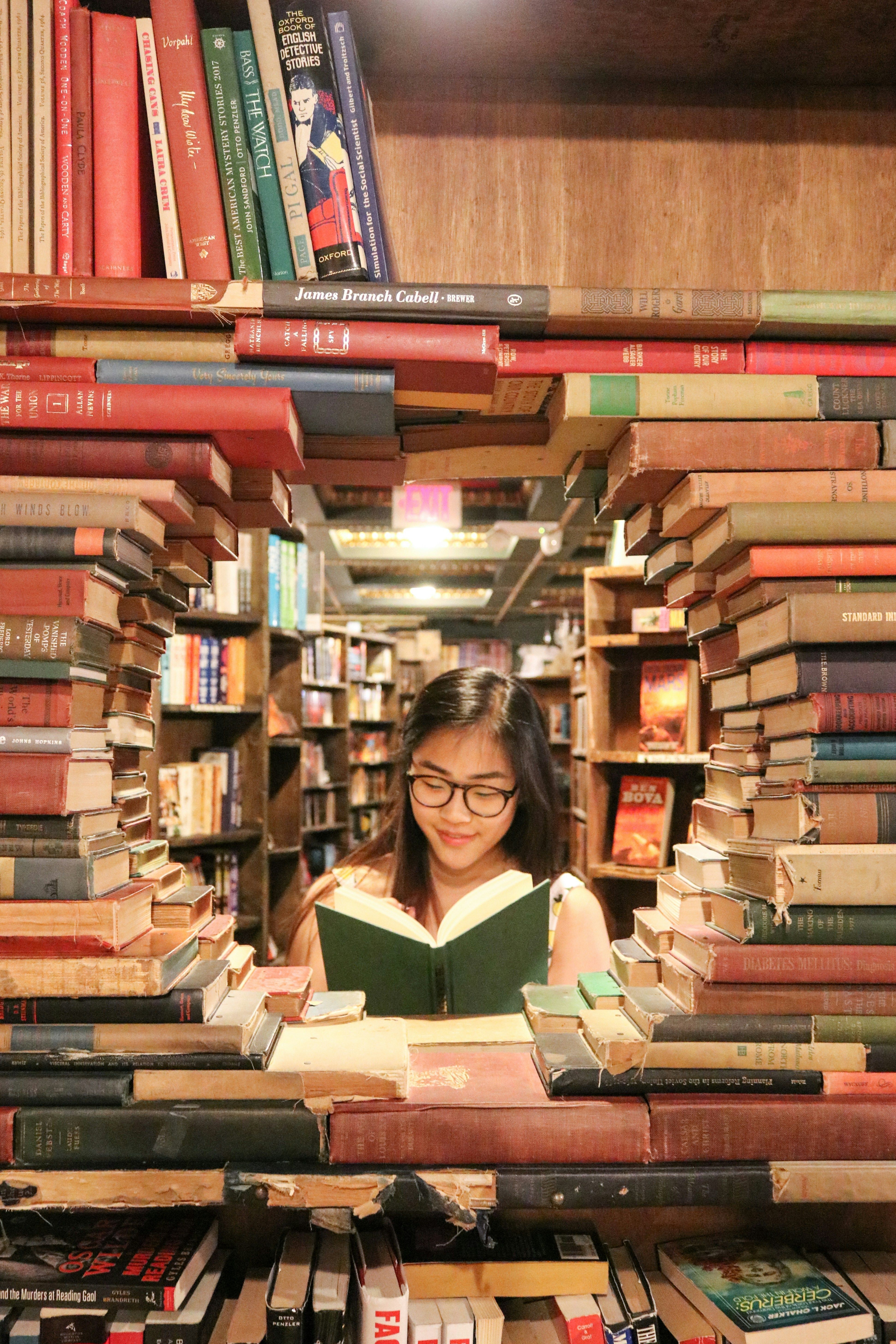 Girl surrounded by books while reading a book