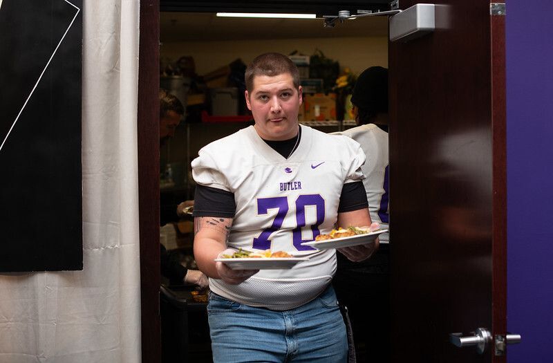 A Butler football player helps serve dinner.