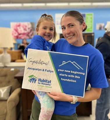 Jacqulyn holds her daughter Fallyn with a sign that reads" Congratulations Jacquelyn and Fallyn. Your new beginning starts with this foundation""