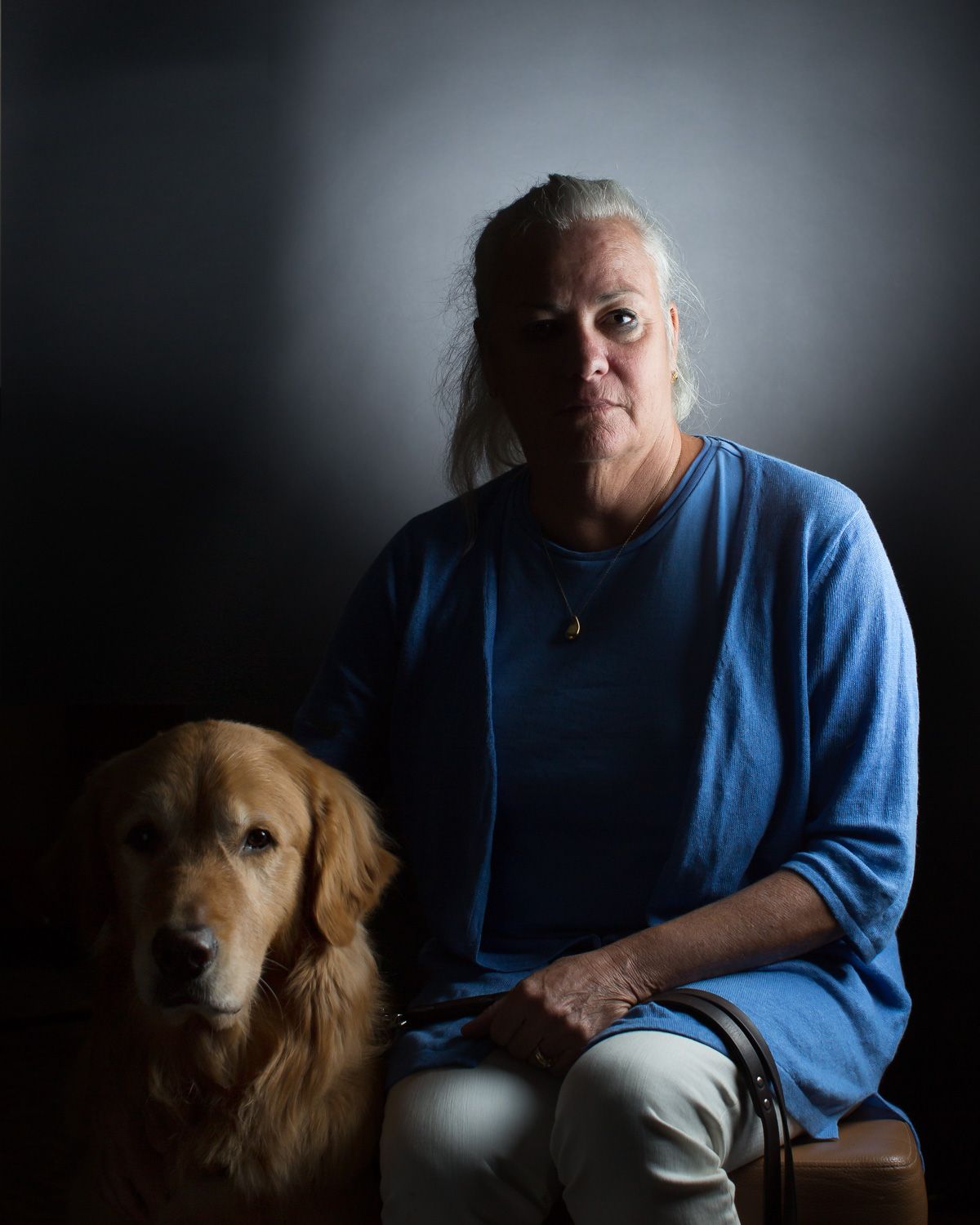 Photo of Moira Shea with her guide dog Finnegan. Half of their faces are in shadow for the Shine a Light on Usher Syndrome project.