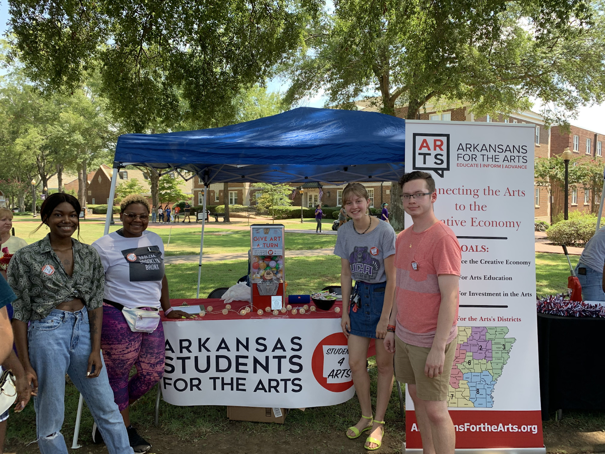 UCA Students for the Arts Members gather around a booth with activities and informational displays at the Conway Daze Festival.