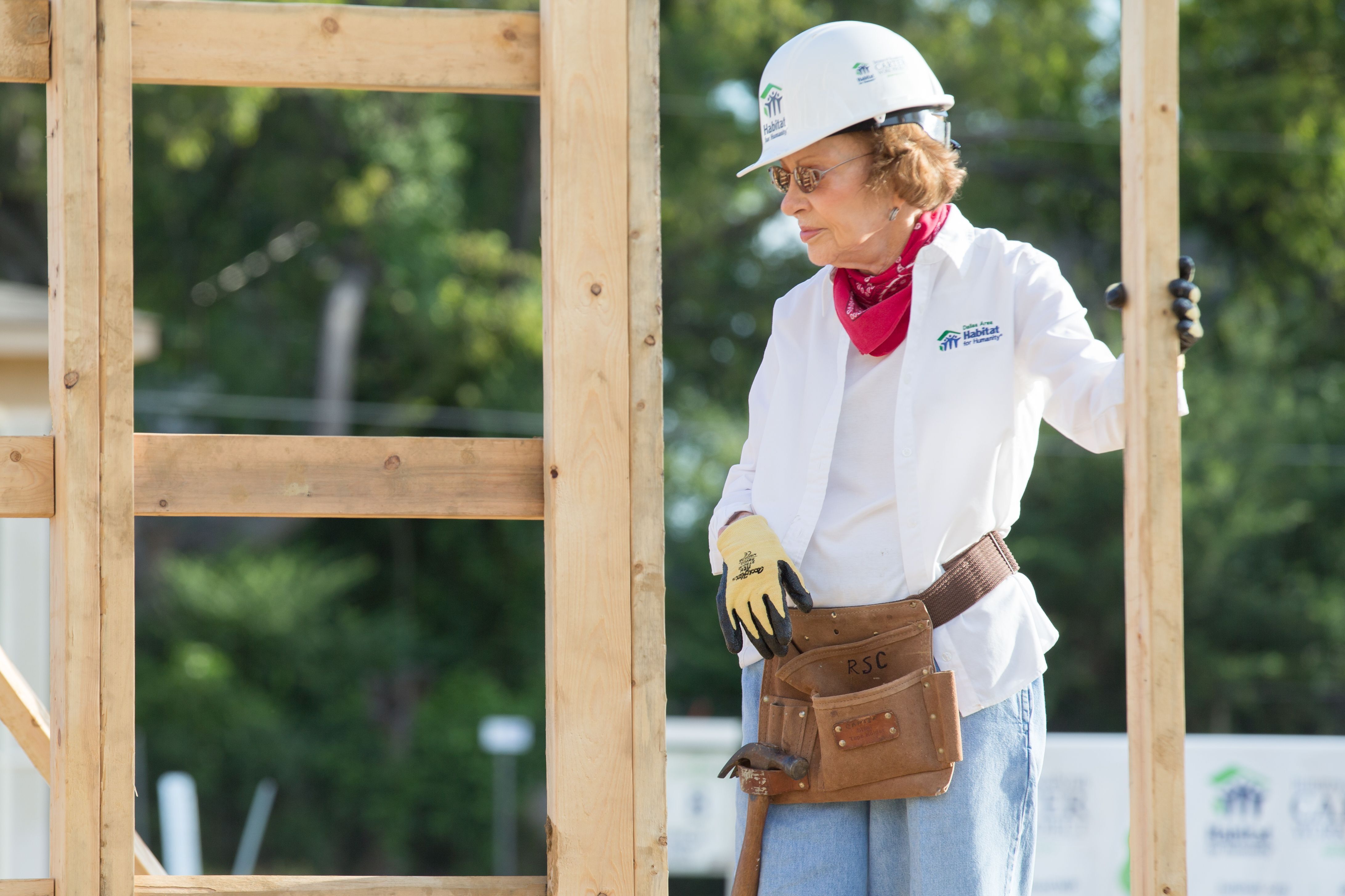 First Lady Rosalynn Carter standing on a Habitat for Humanity construction site wearing a hard hat and toolbelt.