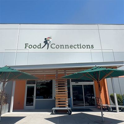 Happy and helpful Redwood Empire Food Bank staff member standing in front of the Food Connections Resource Center 