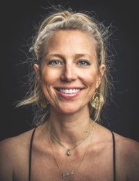 Kathryn Tucker, Executive Director of Arkansas Cinema Society - This pohot is a headshot. She smiles at the camera. Her blonde hair is in a an informal updo and she wears large gold scarab beetle earrings. 