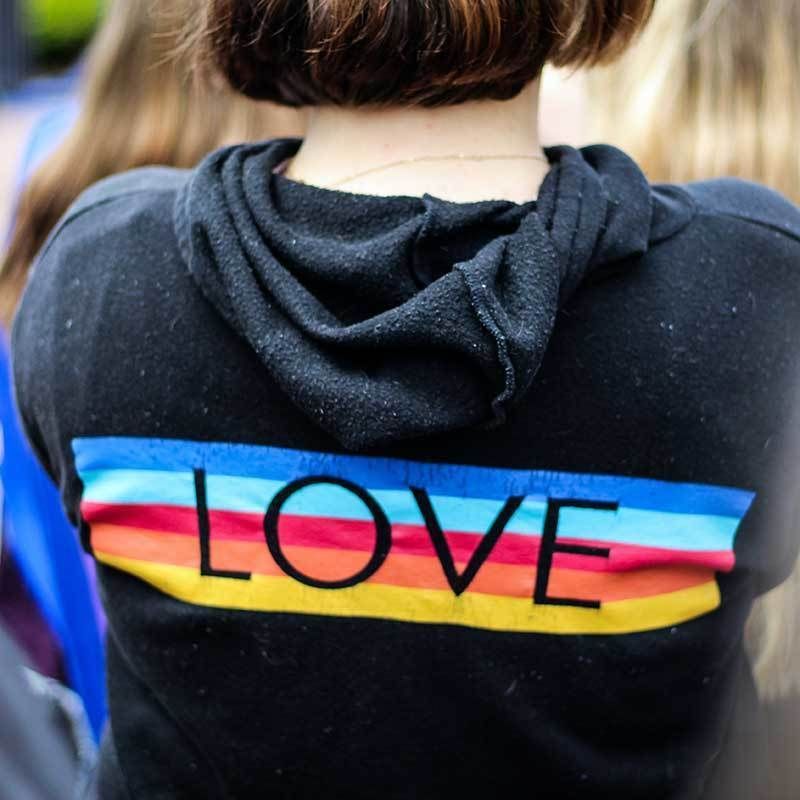 A grey hooded sweatshirt with the word LOVE printed over rainbow stripes.