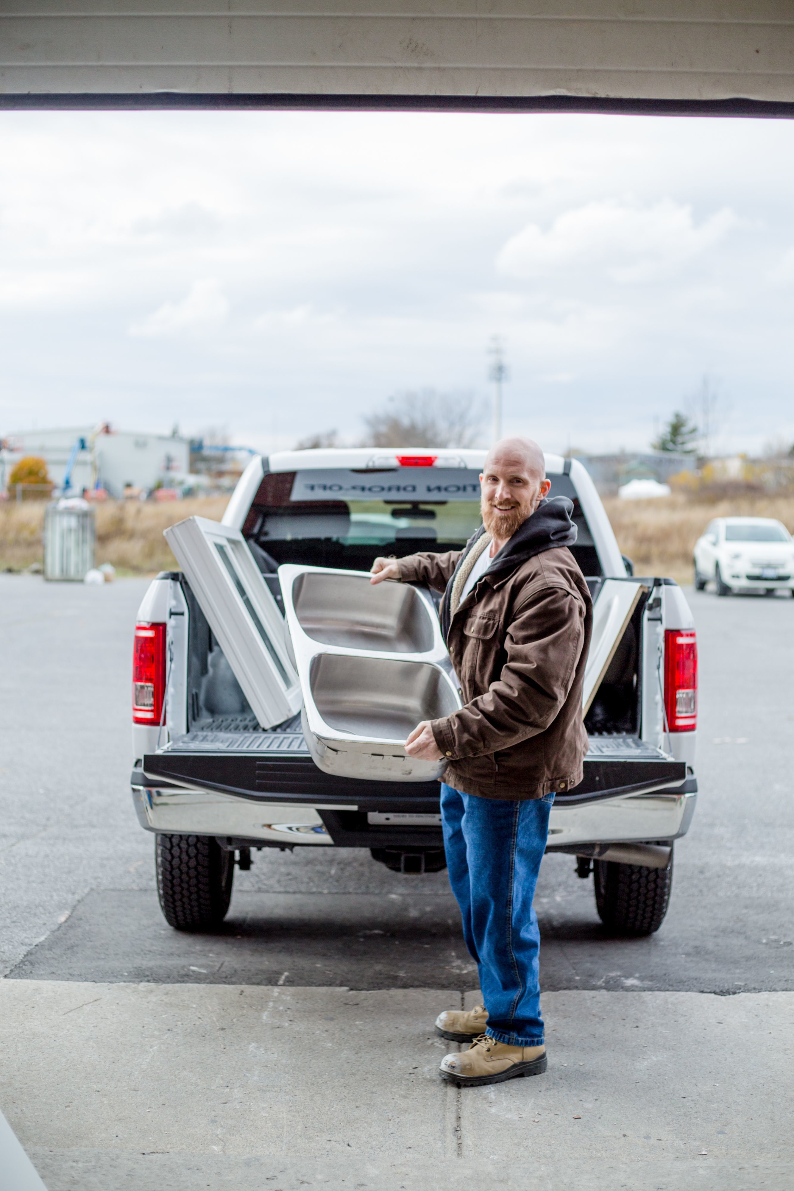 A man in a brown jacket carries a sink to donate to Habitat. 