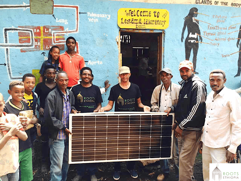 Group of people holding a solar panel.