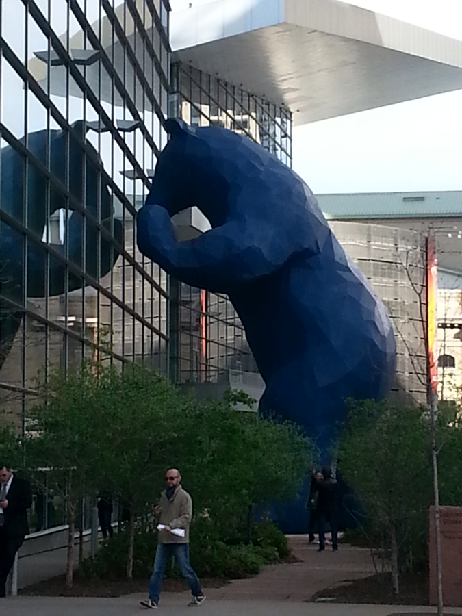 A picture of a 40-foot-tall Blue Bear sculpture peeking into a window