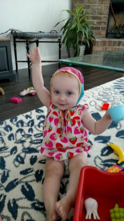 Photo of Emma playing with toys while her hand is raised