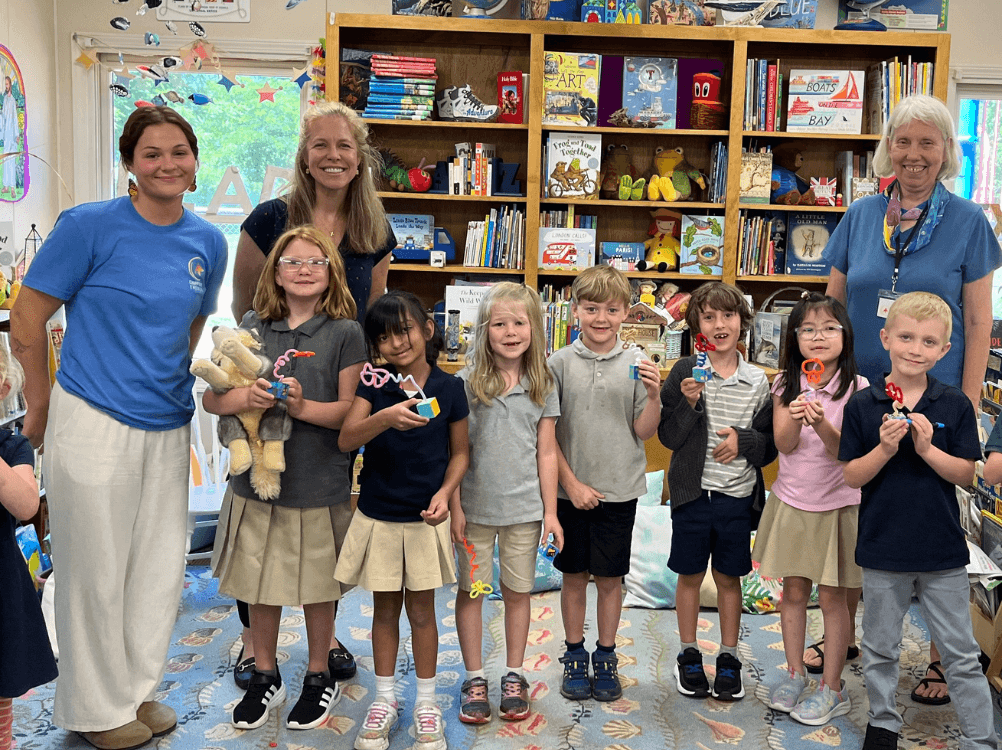 Volunteers and students showing off their pipe-cleaner sculptures