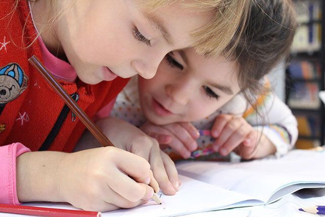 Girls on desk looking at a notebook.