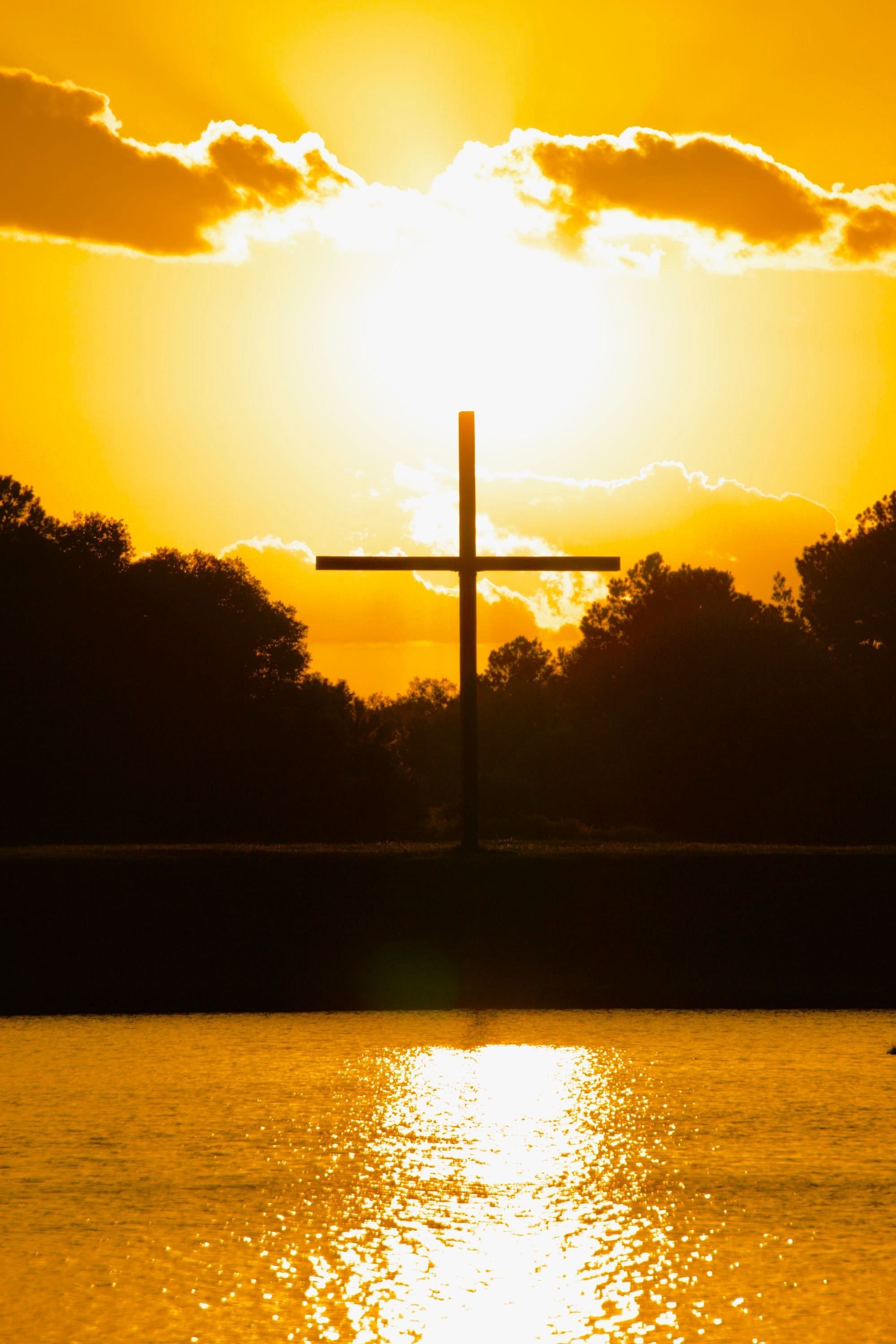 A wooden cross in front of a sunset. 