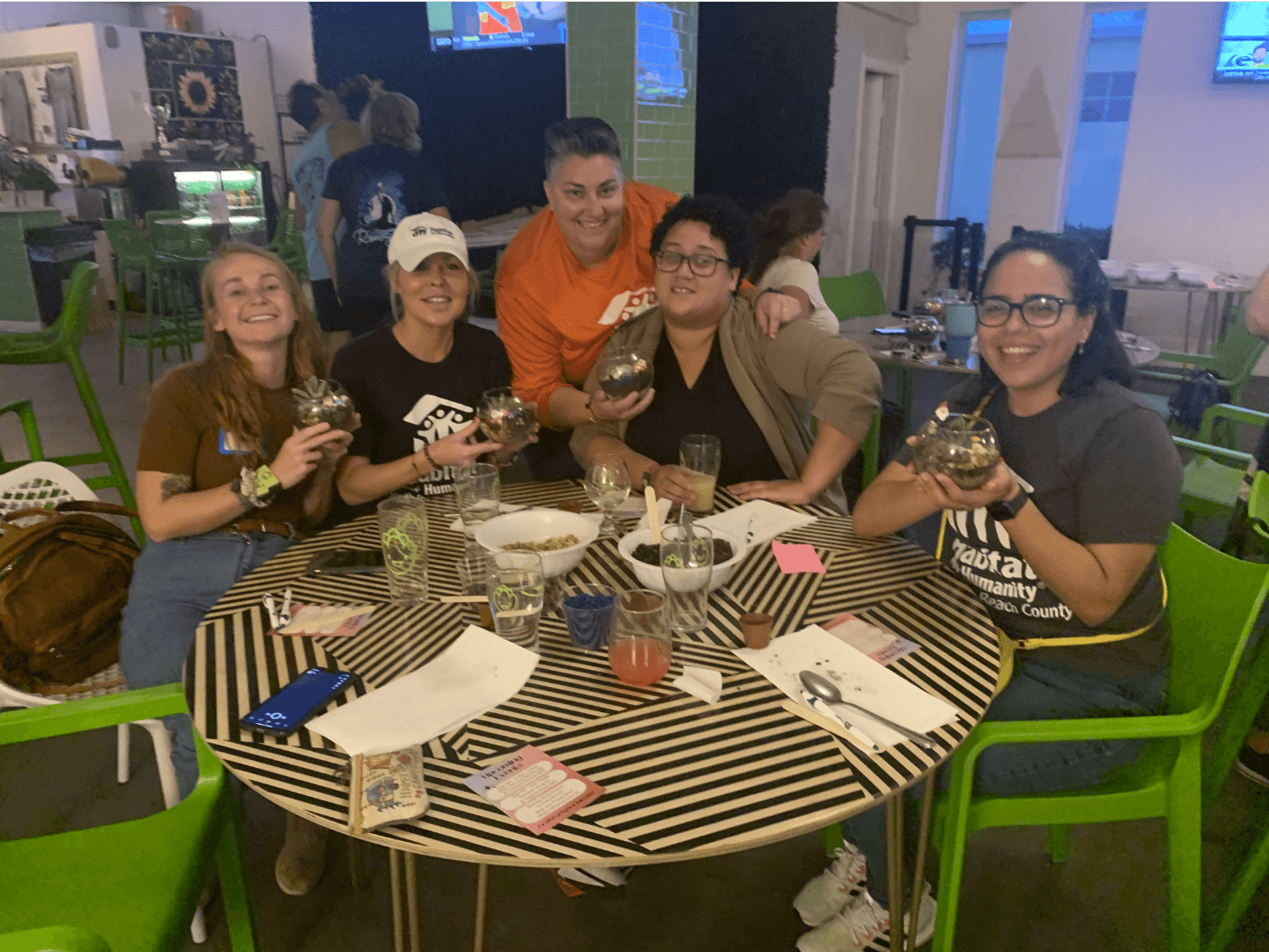 5 people around a table show off the terraniums they crafted