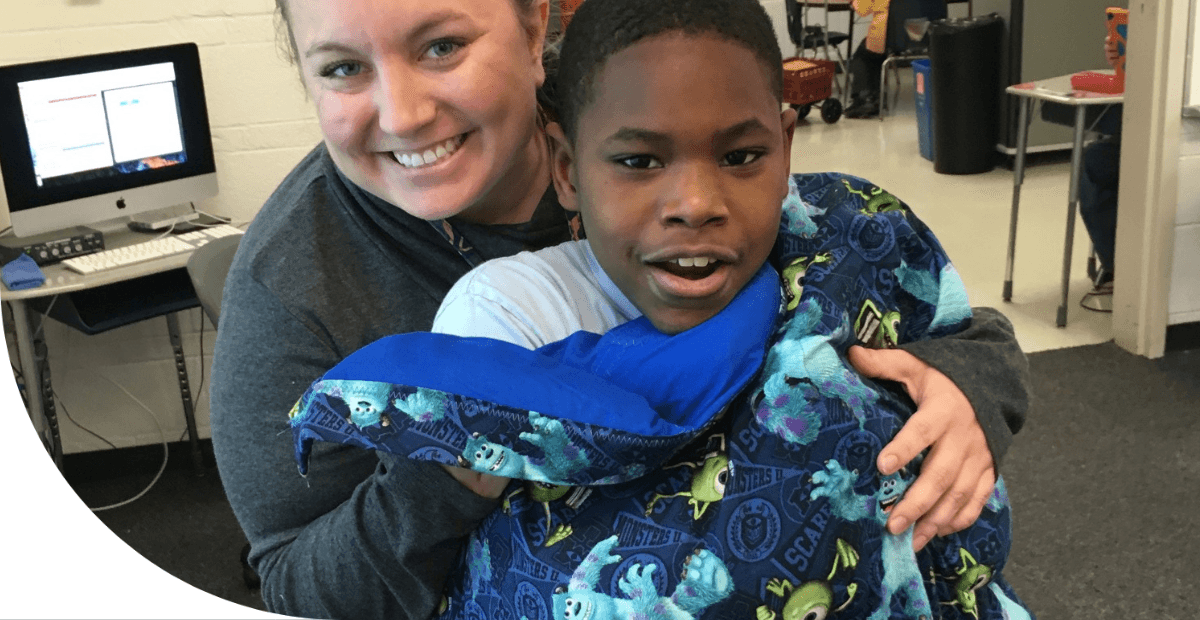 teacher wrapping a boy in a blanket
