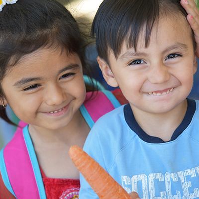 Young boy and girl holding a carrot and laughing