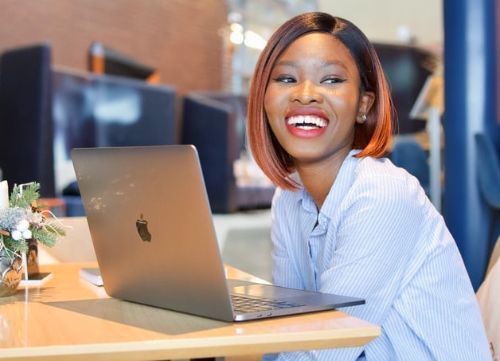 Woman smiling sitting at a table with a laptop computer