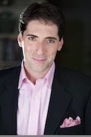 Nicholas Viselli, Artistic Director. A man who is in his 50's and he is wearing a suit with a pink shirt and posing for the picture.