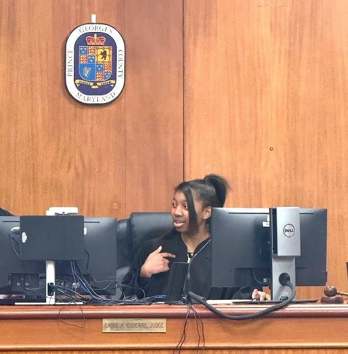 African American female student sitting in judge seat