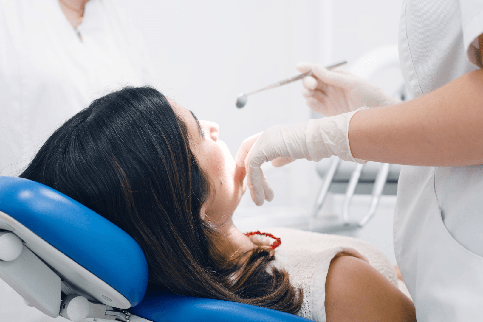a brunette woman in a bright dental office gets a dental cleaning from her dentist