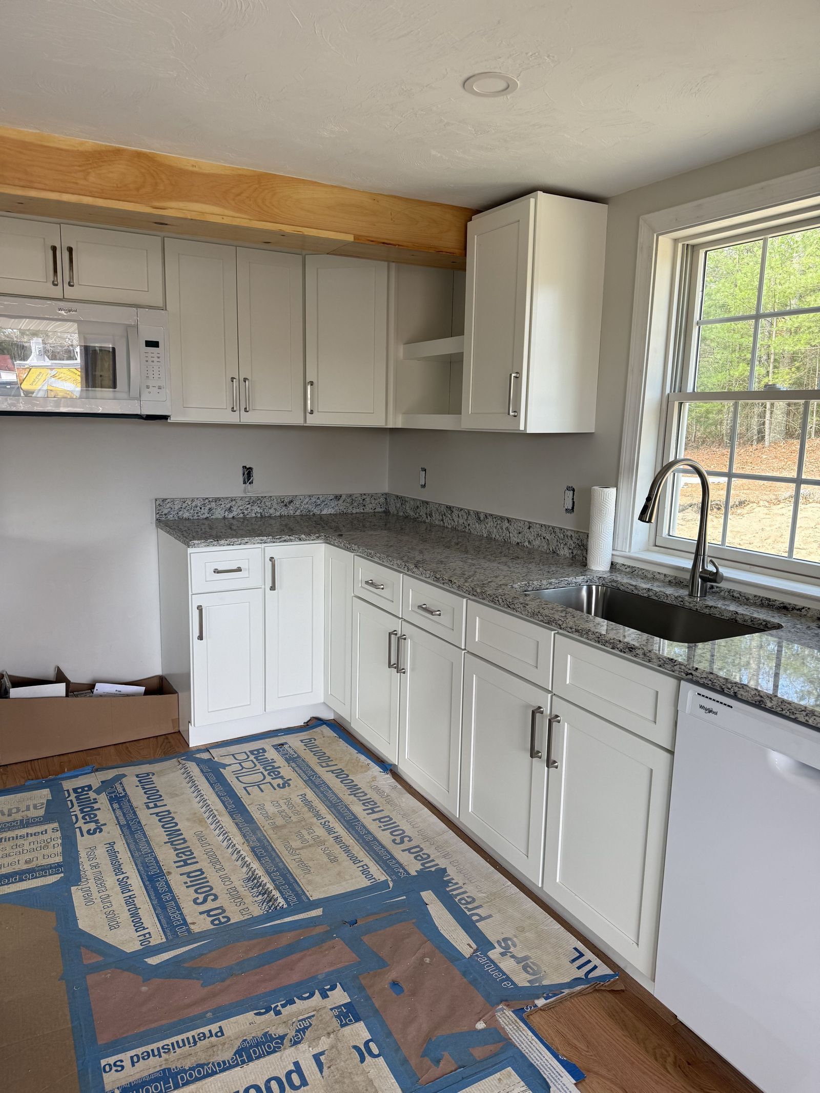A photo of white kitchen cabinets with a new grey and black granite countertop installed