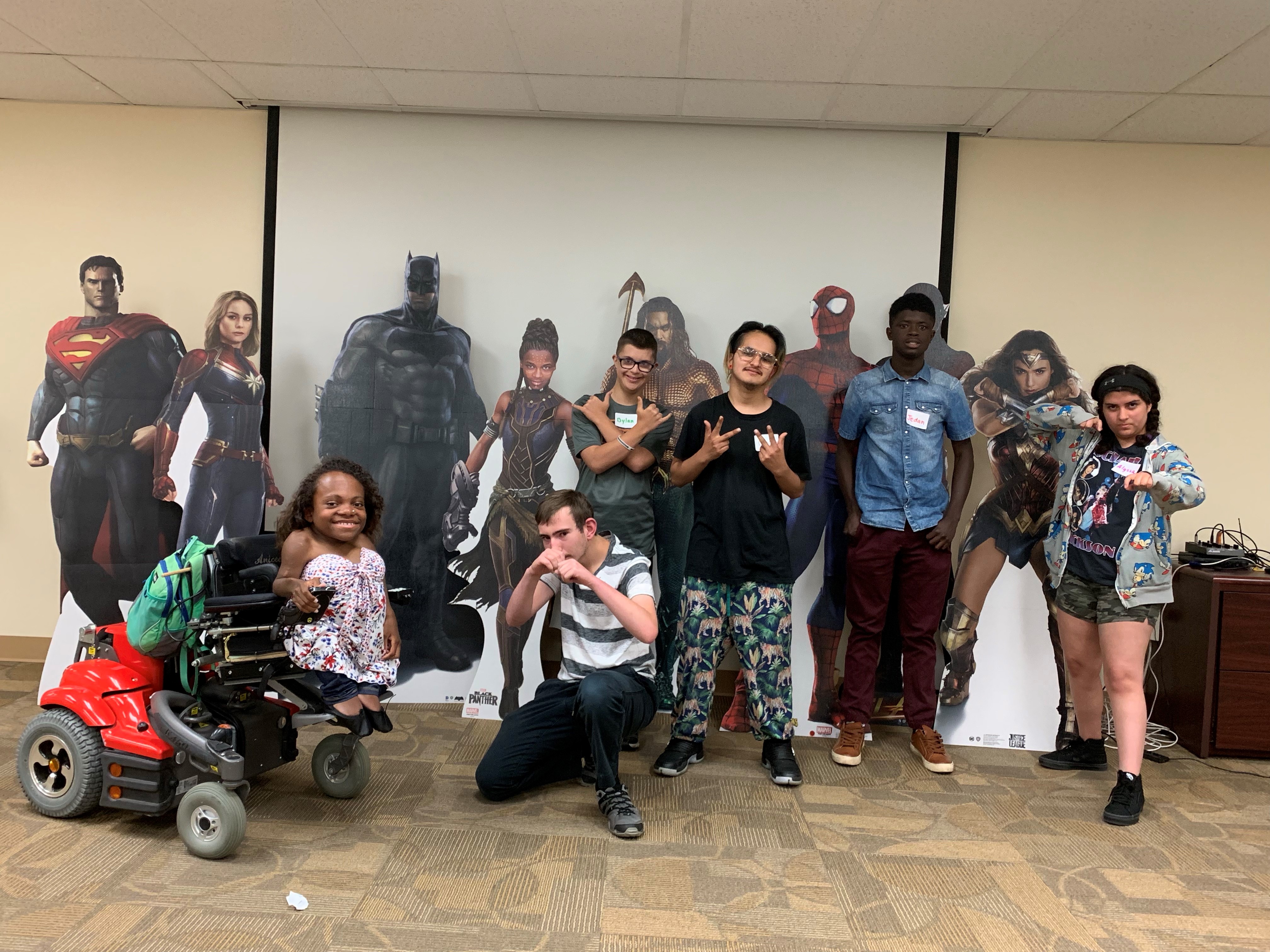 A group of teens pose with superhero cut outs at The Arc's offices