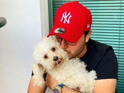 Man holding a small white dog in embrace