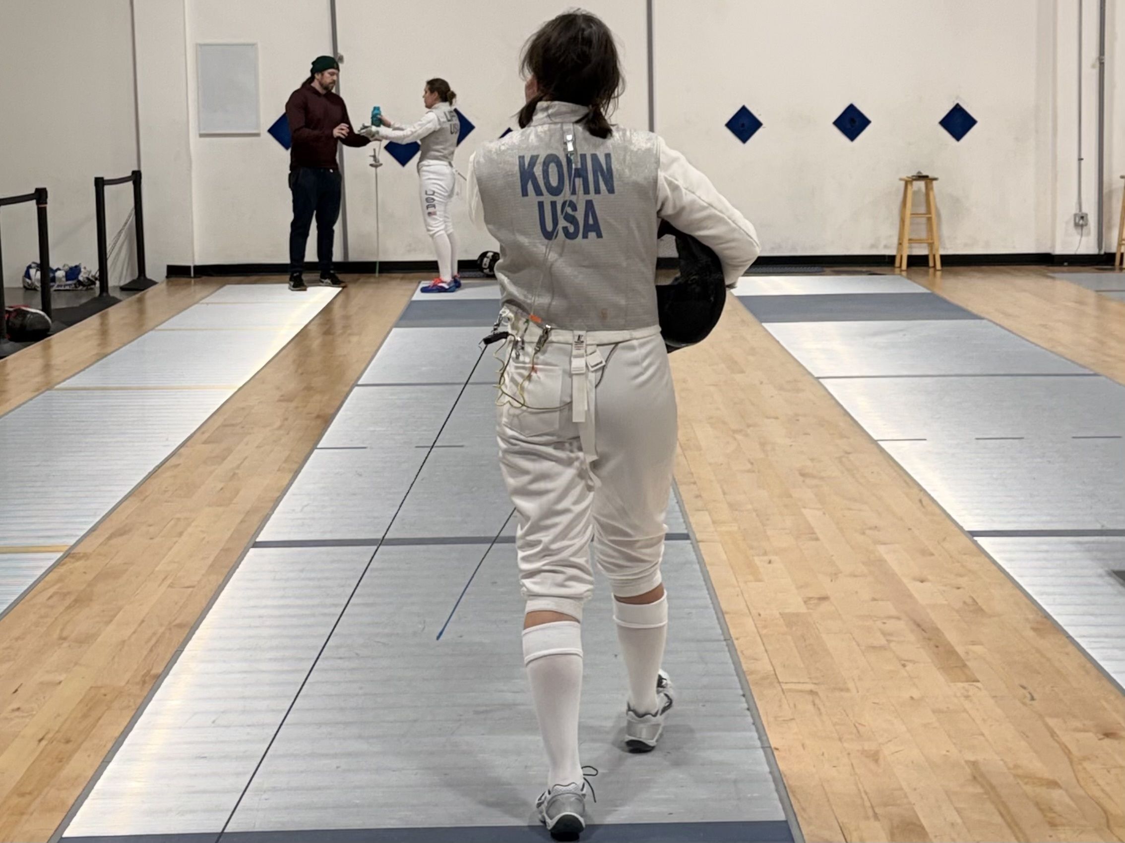The back of a fencer's lame reads "KOHN"