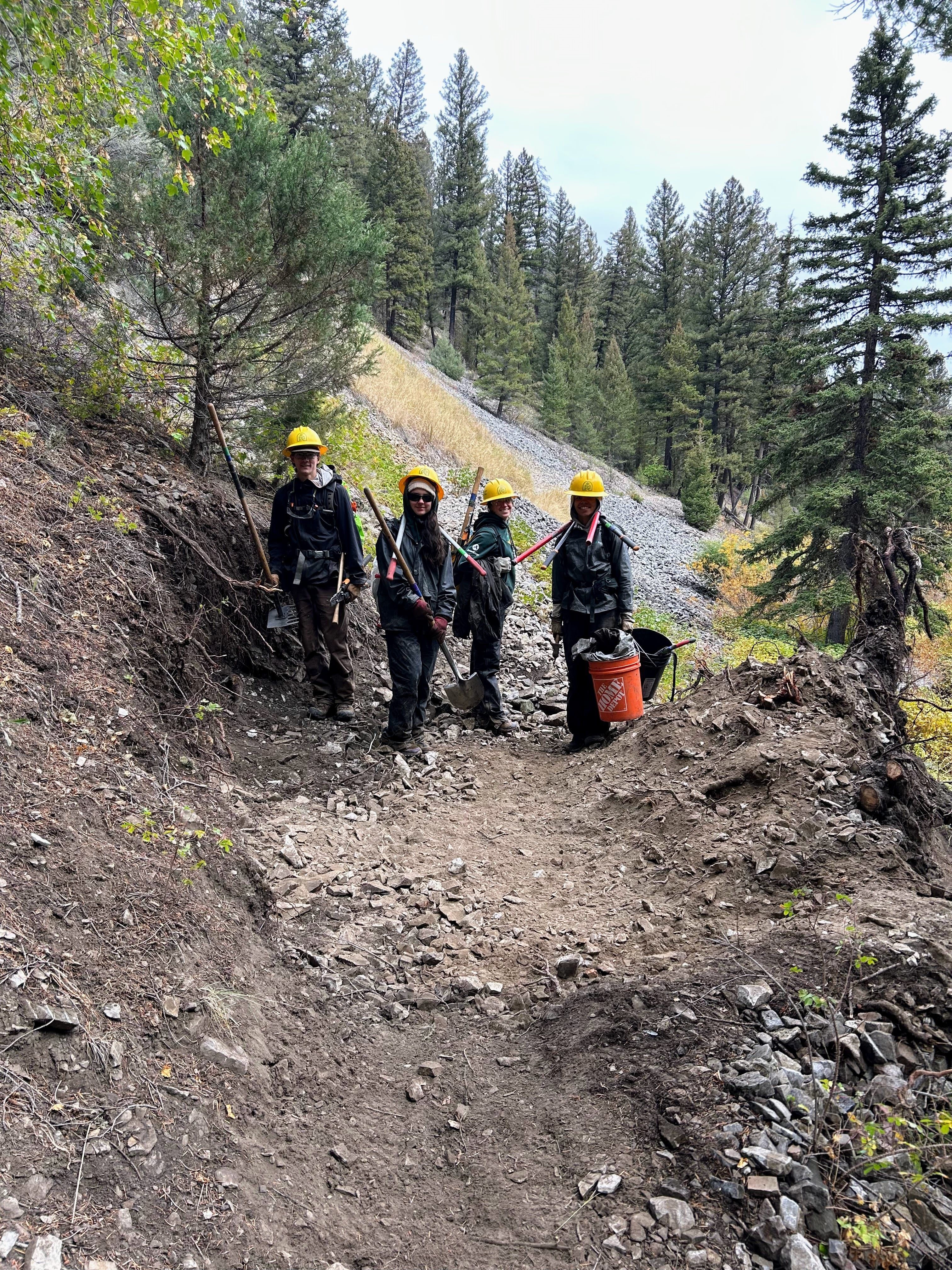 Crew members stand on a trail that they're working on, posing for the camera.