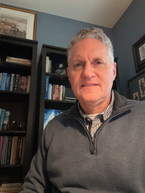 Portrait of Gerald H. Ankeny, and man sitting in front of bookshelfs.