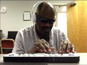 A man sitting using the Braille Edge 40, Apple iPad and Bluetooth keyboard to connect with friends and family