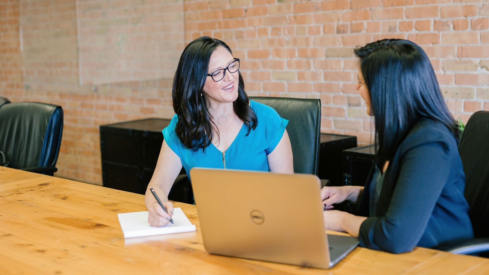 Two women working together on paperwork with a laptop