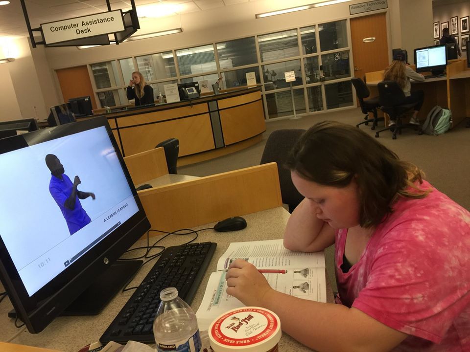 Student with down sydrome studying sign language book in library