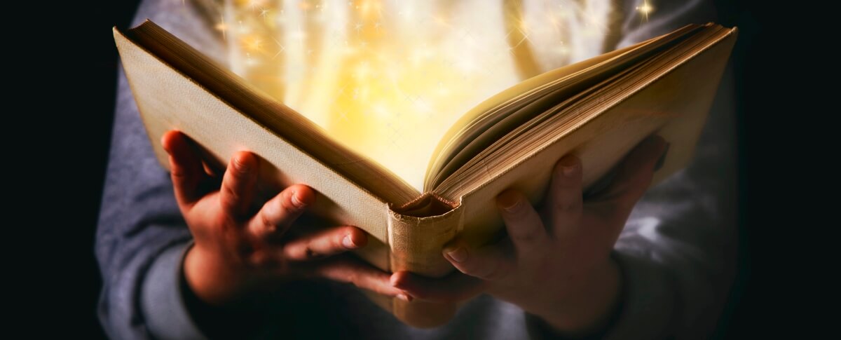 storytelling: a boy holding a book with sparks coming off the page like magic