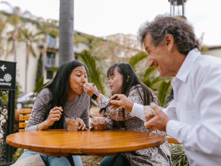 Parents and teen eating ice cream outside.
