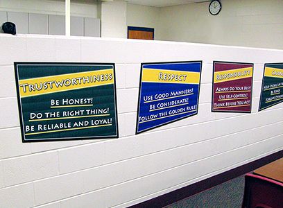 Durable school signs showing character values in trapezoid shape. 4 custom signs on school wall.