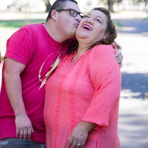 adult son with disability kisses laughing mom