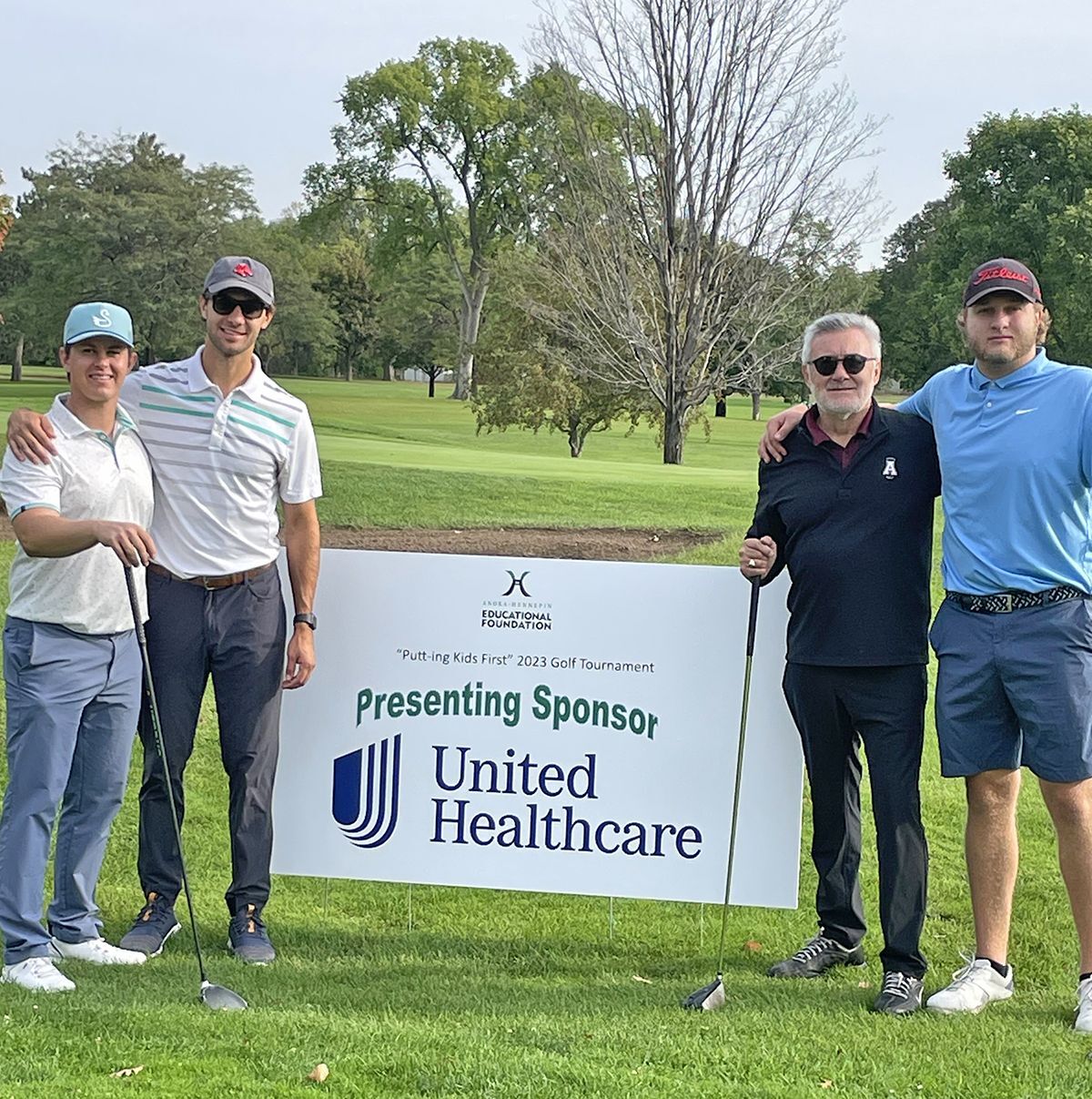 Golfers beside a United Healthcare sponsor banner