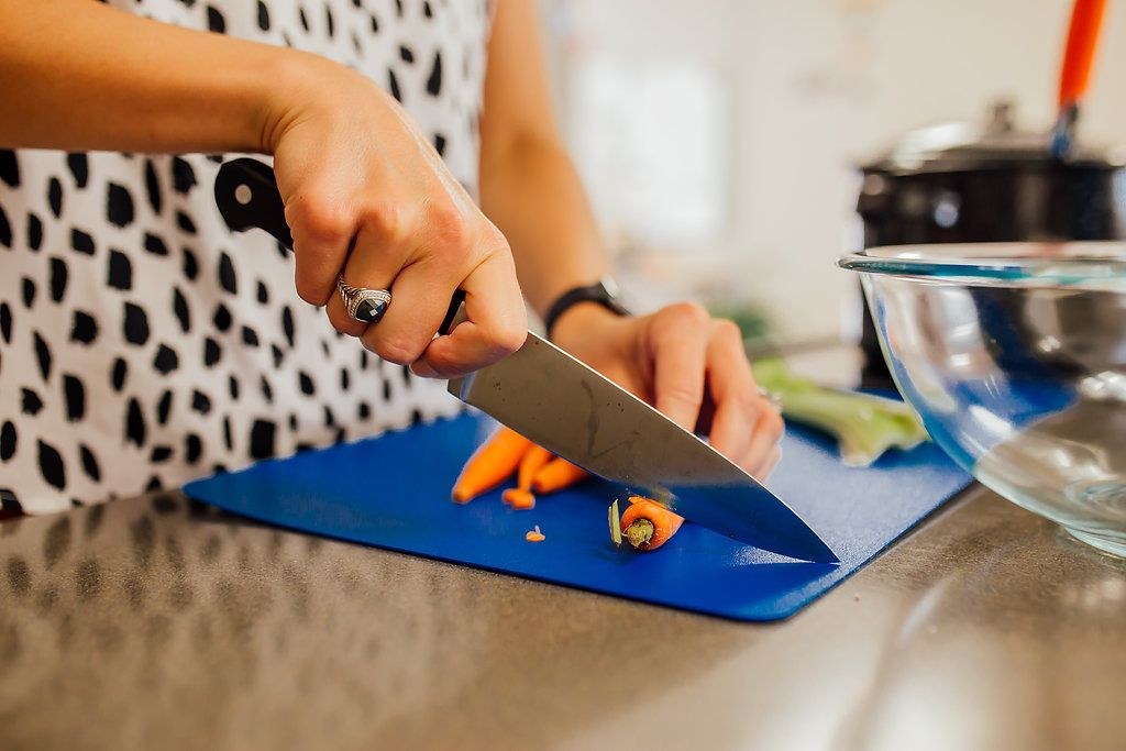 Woman using a knife to cut a carrot.