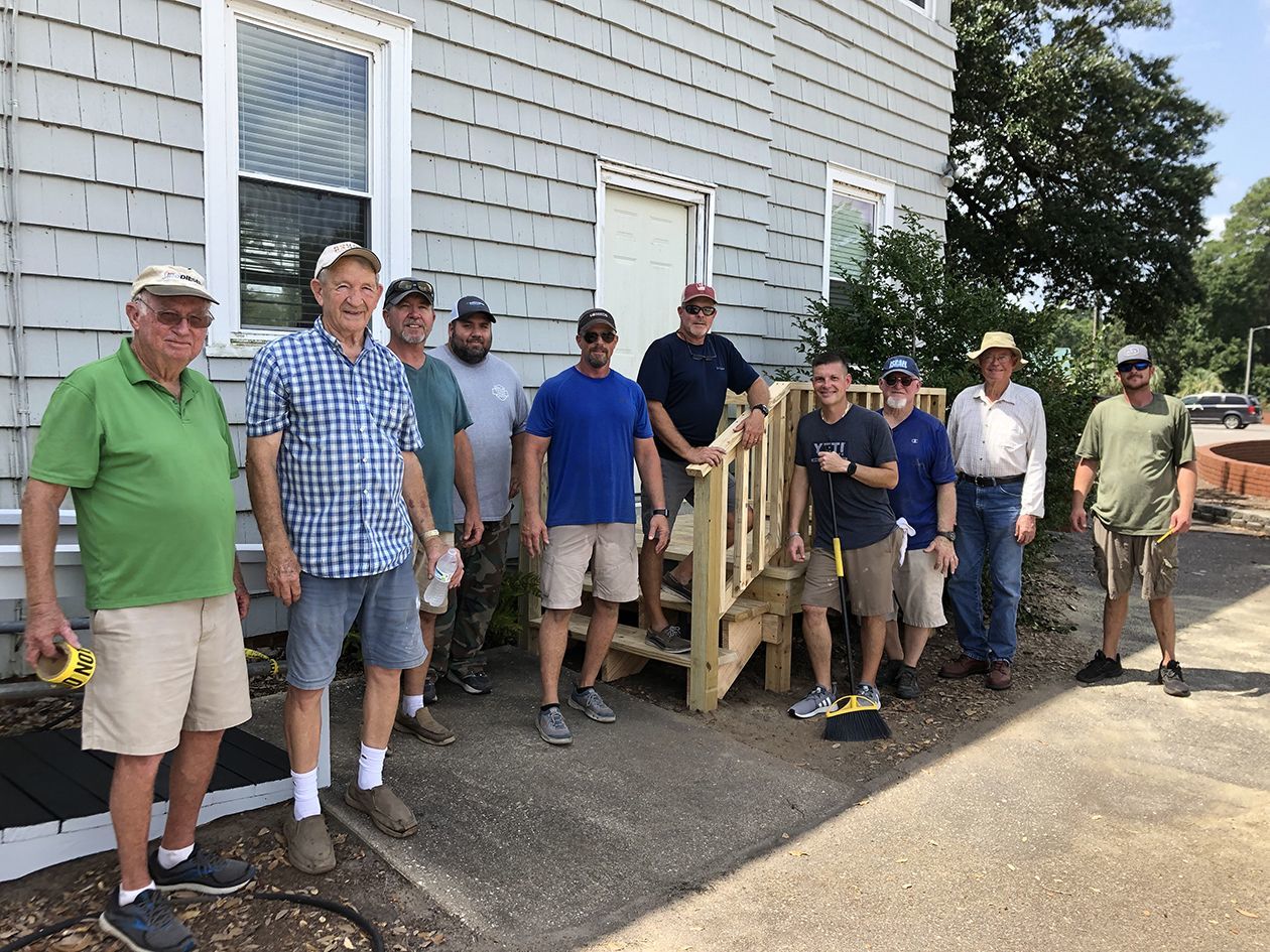 Volunteers from the Piney Forest Baptist Church stand with the stairs rebuilt at Flemington Hall at BGHNC