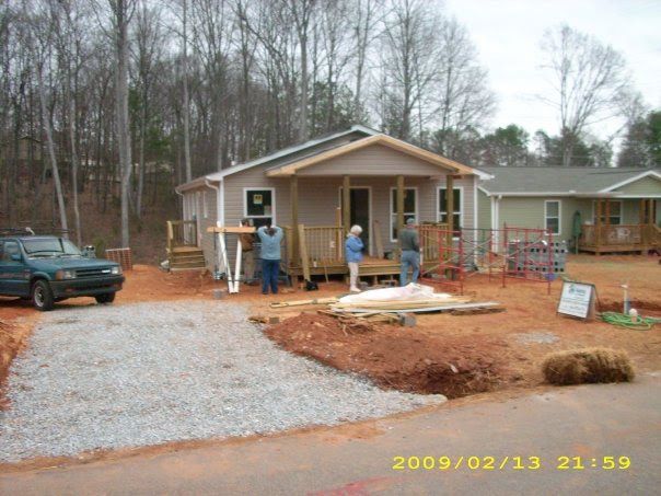 A house with tan siding and a newly graveled driveway.