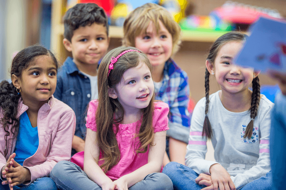 group of preschool aded children listening to a book being read