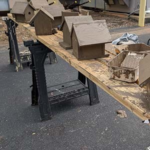 Row of wooden birdhouses lined up on a sawhorse table outdoors