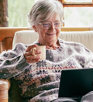 Older woman sits with tea and her tablet