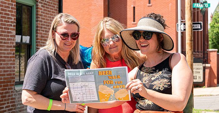 Three ladies looking at a Beer Walk map in 2023