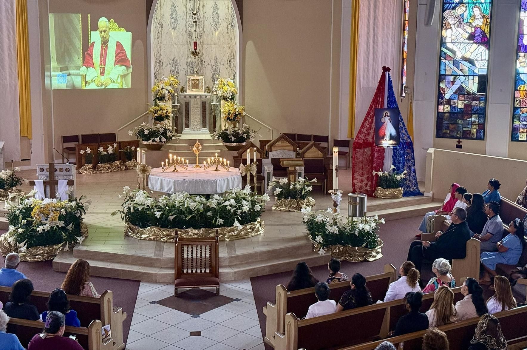 The faithful watch the video feed from Rome with Pope Leo XIV at Holy Name of Jesus Church in West Palm Beach April 11, 2026