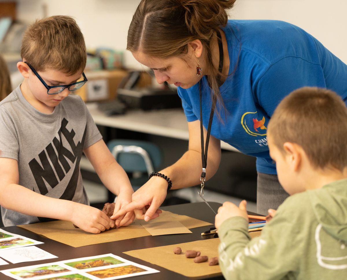 Facilitator helping students sculpt wildlife with clay