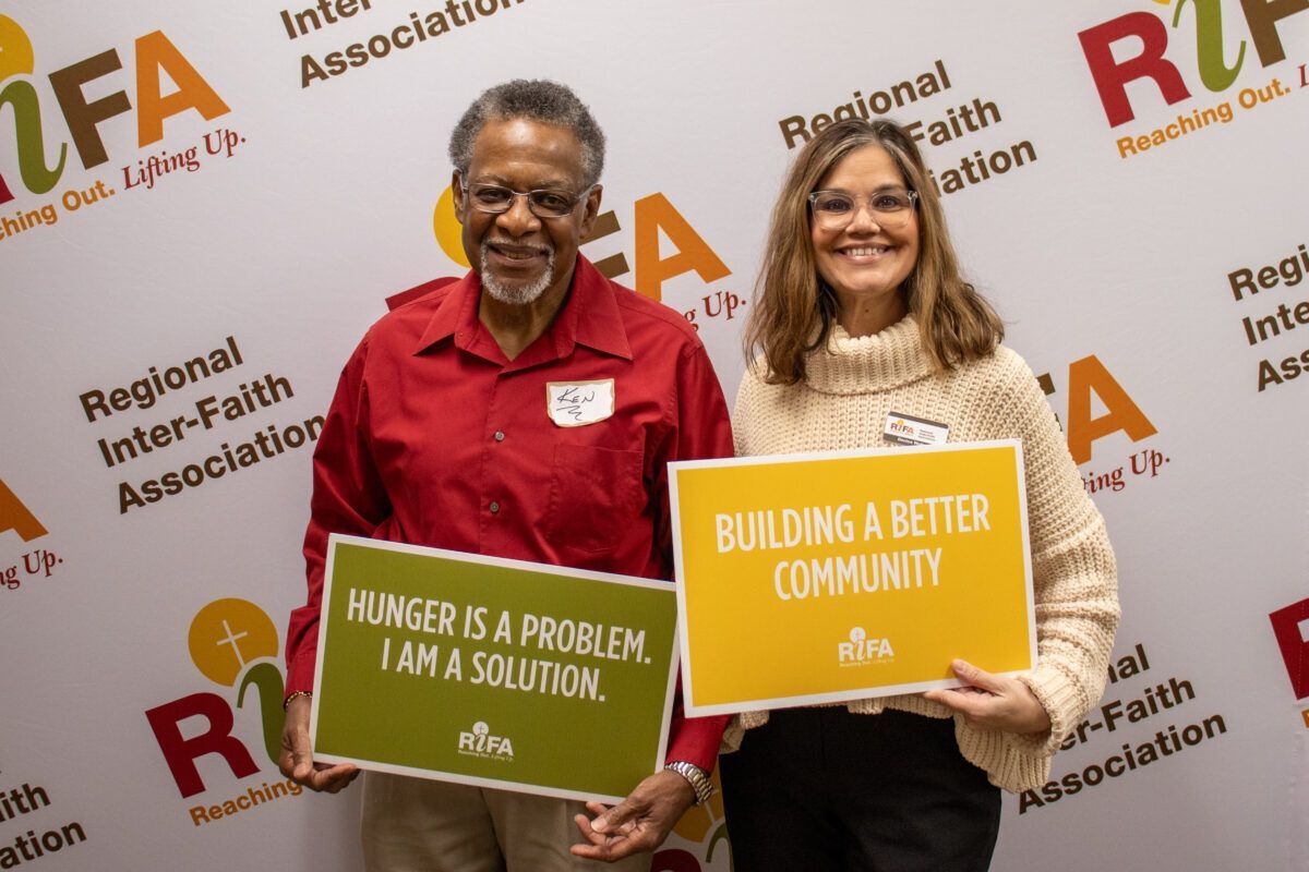 Two people holding signs related to combating hunger