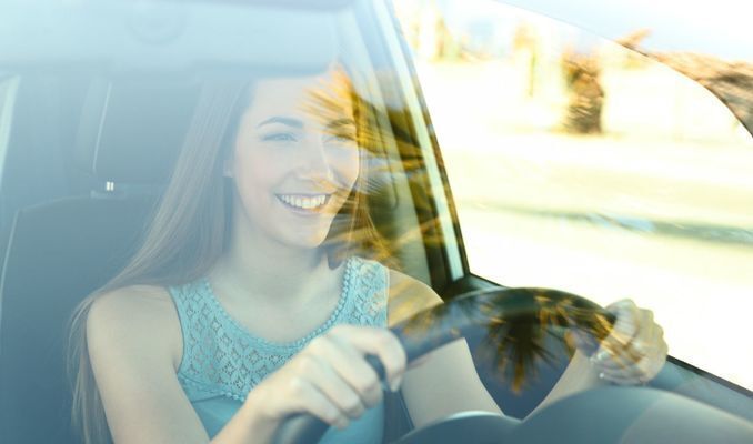 young woman behind the wheel of a car, smiling