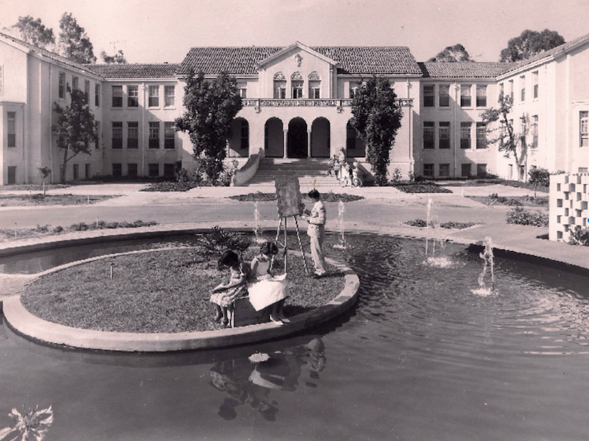 An historial photo of David & Margaret's Whitney Building from the 1930s. Two children are reading while a young man paints by the old pond in front of the building.